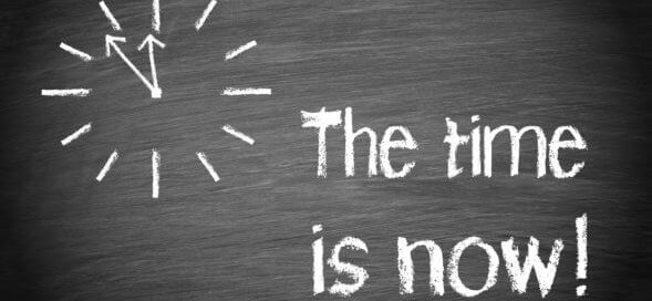 "The Time is Now" written in white chalk with drawn clock